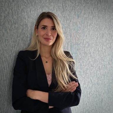 Blonde Frau mit gekreuzten Armen vor einer Wand