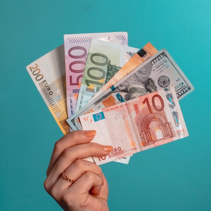 Weibliche Hand hält aufgefächerte Euro- und Dollarscheine